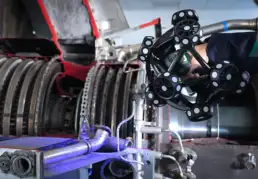 Engineer using a handheld 3D scanner with optical markers to inspect and scan the interior components of an industrial machine.
